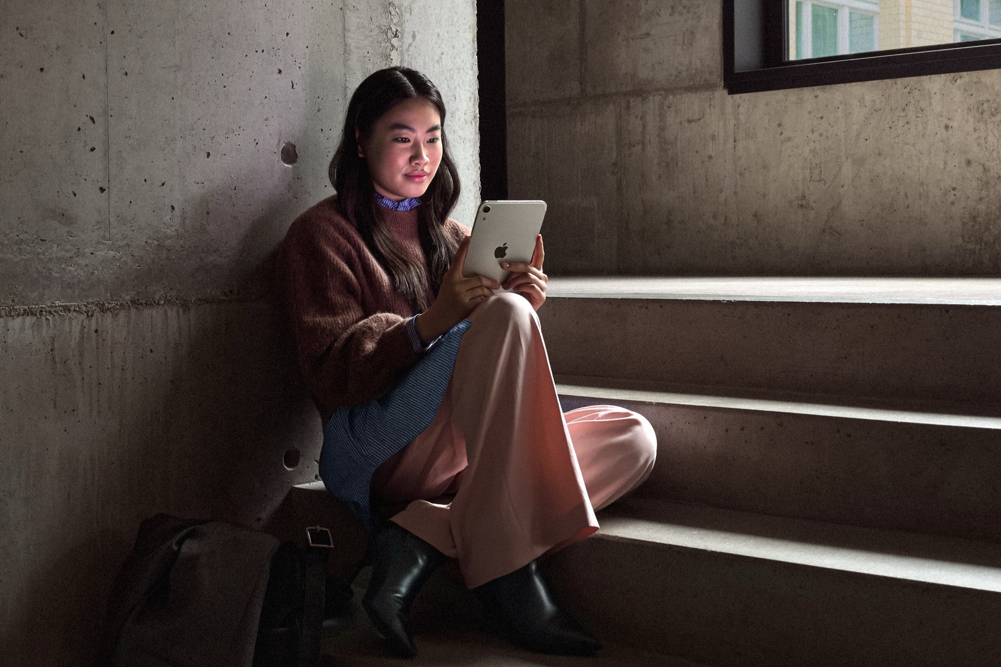 階段でiPad miniを使う公式の使用イメージ。背面と片手で持った大きさの参考